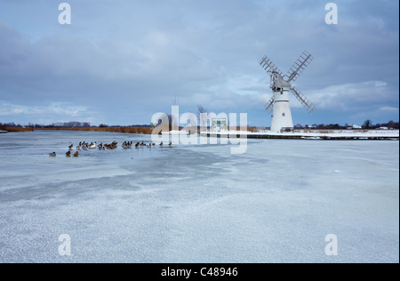 Un parzialmente congelati fiume Thurne con il mulino a vento di Thurne in background, Norfolk Broads Foto Stock