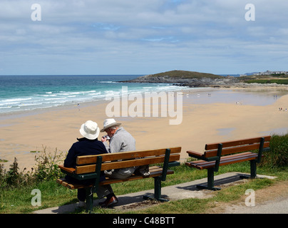 Una coppia di anziani seduti su una panchina affacciata Fistral Beach in Newquay, Cornwall, Regno Unito Foto Stock