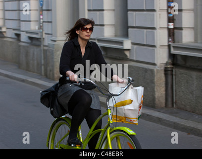 Una giovane donna cavalca un giallo in bicicletta attraverso le strade di Lucerna, Svizzera. Foto Stock