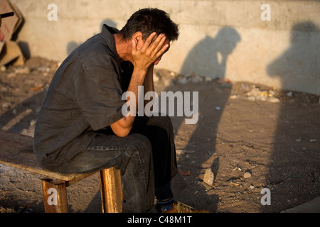 Una centrale di migranti americano viaggia in Messico per lavorare negli Stati Uniti coprire la sua faccia come egli siede a un rifugio in Ixtepe Foto Stock