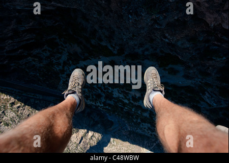 I piedi di un uomo si aggirano sulla i-70 e sul fiume Colorado nel Glenwood Canyon mentre si trova sull'altalena gigante delle Glenwood Caverns Adventure P Foto Stock