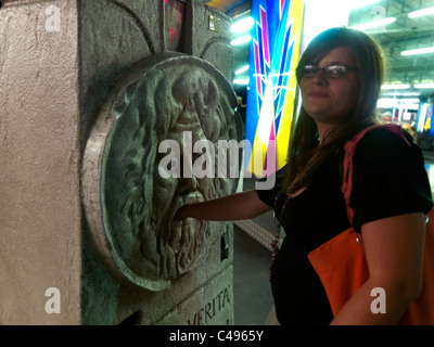 Catania Sicilia Italia Parco Divertimenti PARCO Nettuno adolescente di mettere la sua mano nella bocca di una replica della Bocca della Verita' Foto Stock