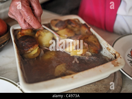Femmina - pensionati anziani che serve fino a Lancashire hot pot per la cena REGNO UNITO Foto Stock