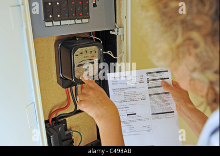 Donna contemplando l'aumento dei prezzi dell'energia e delle fatture nel Regno Unito come lei legge il suo contatore elettrico Foto Stock