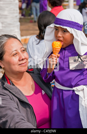 Settimana Santa (Semana Santa) in Antigua con il bambino a mangiare il gelato che indossa il viola rebes come partecipante alla ricorrenza annuale Foto Stock