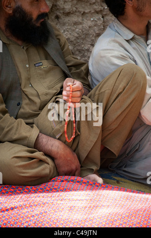 Uomo con la preghiera di perline in Helmand in Afghanistan Foto Stock