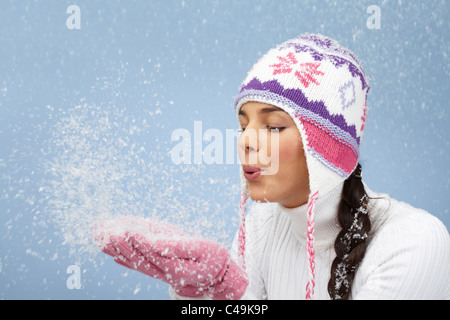 Immagine di Pretty Woman in rosa e guanti a maglia Cappello invernale lavori di soffiaggio della neve dai suoi palmi Foto Stock