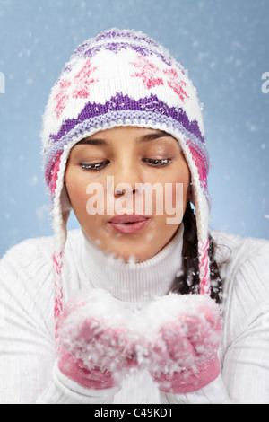 Immagine di Pretty Woman in rosa e guanti a maglia Cappello invernale lavori di soffiaggio della neve dai suoi palmi Foto Stock