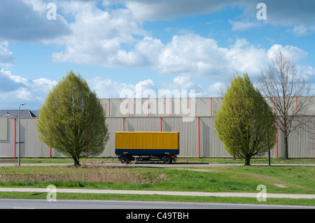 Giallo rimorchio parcheggiato di fronte a un magazzino Foto Stock