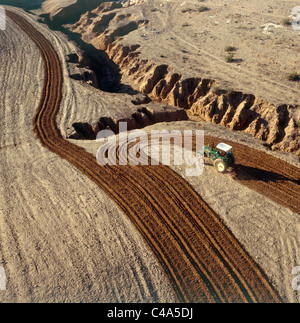 Fotografia aerea di un trattore arare un campo nel nord del deserto del Negev Foto Stock