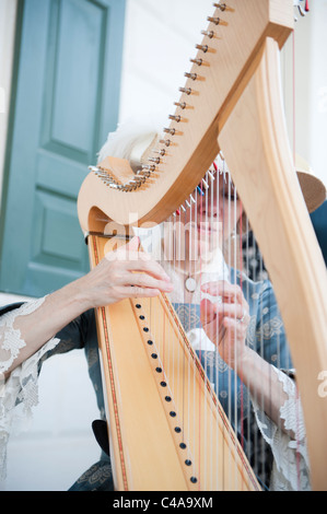 Una Donna vestita nel XVIII secolo abbigliamento suonare l'arpa a Mount Vernon Estate in Alexandria, Virginia. Foto Stock