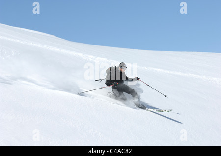 Un uomo telemark in profonda di polvere fresca neve sotto un cielo blu chiaro in Dizin Iran Foto Stock