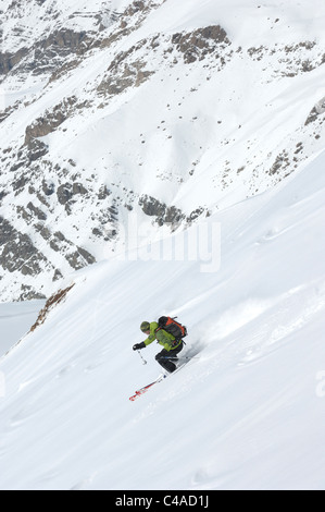 Un uomo sci indossando uno zaino i fuori pista in neve fresca sotto un cielo blu in Dizin resort parte delle montagne Alborz in Iran Foto Stock