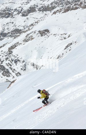 Un uomo sci indossando uno zaino i fuori pista in neve fresca sotto un cielo blu in Dizin resort parte delle montagne Alborz in Iran Foto Stock