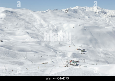 Dizin ski resort in Alborz montagne di Iran sotto un cielo blu e la caduta di neve Foto Stock