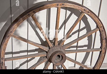 Un vecchio e rustico ruota di carro si appoggia contro un edificio in Jackson Hole, Wyoming negli Stati Uniti. Foto Stock