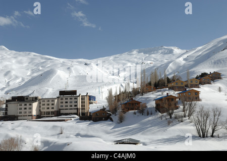 Dizin ski resort in Alborz montagne di Iran sotto un cielo blu e la caduta di neve Foto Stock