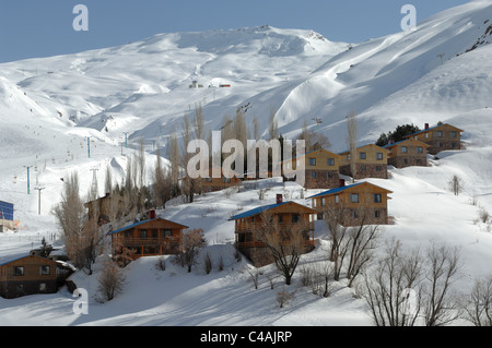 Dizin ski resort in Alborz montagne di Iran sotto un cielo blu e la caduta di neve Foto Stock