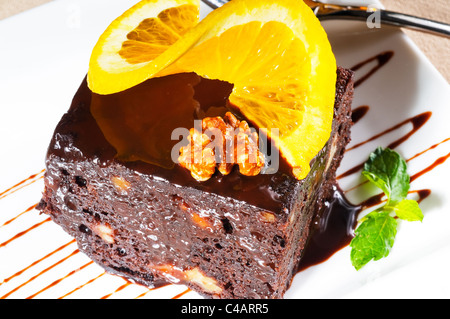 Freschi di forno delizioso cioccolato e noci torta con fetta di orance sulla parte superiore e foglia di menta Foto Stock