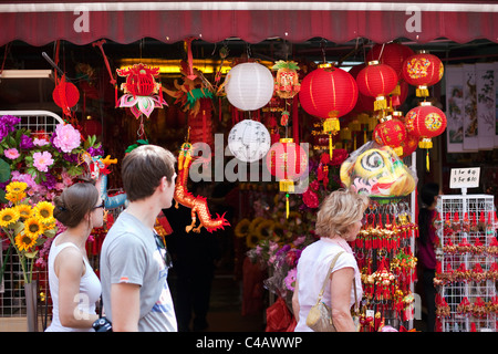 Singapore, Singapore, Chinatown. I turisti a piedi passato Anno Nuovo Cinese decorazioni per la vendita in Temple Street. Foto Stock