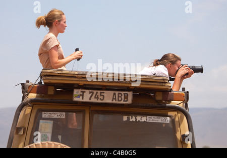 Tanzania, Ngorongoro. Due donne guardare fuori da un veicolo di safari alla fauna selvatica. Foto Stock