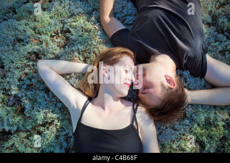 Coppia giovane appoggiato sull'erba nella foresta. Foto Stock