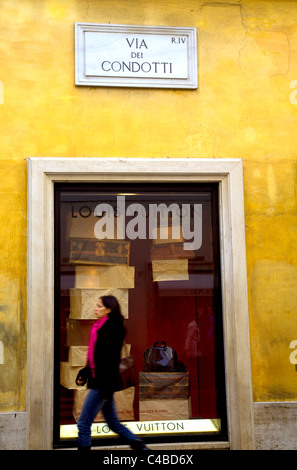 Roma, Italia; una giovane donna che passa davanti a un progettista di negozio di abbigliamento in centro hsitorical. Signor Foto Stock