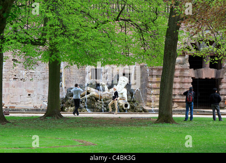 I turisti pongono di fronte alla fontana di Nettuno nei giardini di Schloss Heidelberg, Germania Foto Stock