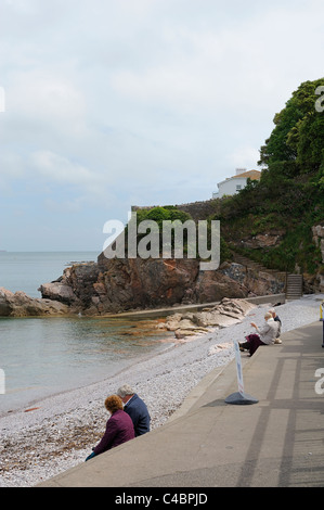 Persone sedute e rilassante sulla spiaggia di frangiflutti Devon England Regno Unito Foto Stock