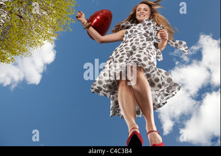 Donna che cammina con palloncino rosso Foto Stock