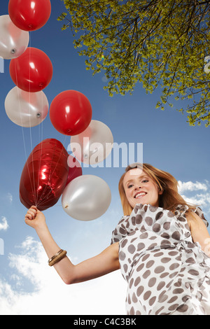 Donna che cammina con il mazzetto di palloncini Foto Stock