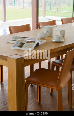 Close-up di cuoio Sedie CABINA (da Bellini per Cassina) e rovere tavolo da pranzo con libri aperti e una tazza di caffè Foto Stock