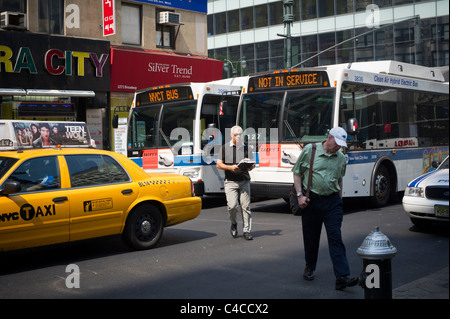 Pedoni croce nel traffico che include due transit NYC autobus nella midtown a New York Foto Stock