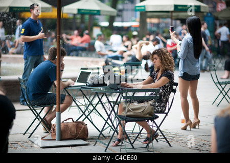 Gli utenti di computer di prendere vantaggio di esistenti di accesso internet wireless gratuito in Bryant Park di New York Foto Stock