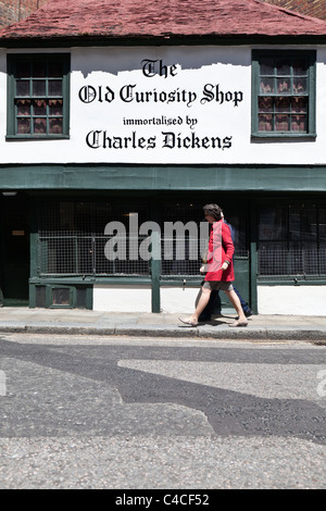 Woman in Red coat a piedi dal Charles Dickens vecchio negozio di curiosità Holborn Londra Foto Stock