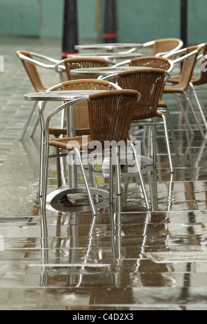 London cafe di sedie e tavoli sul marciapiede sotto la pioggia. Profondità di campo. Foto Stock