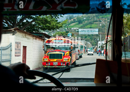 Equitazione in un guatemalteco pollo 'bus' passando due autobus che sopraggiungono nella città di Santa Catarina Barahona vicino a Antigua Foto Stock