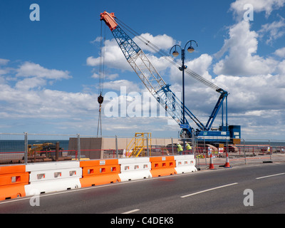 Una gru cingolata erigere pre-calcestruzzo gettato le sezioni di un nuovo muro di mare a redcar cleveland North Yorkshire Giugno 2011 Foto Stock