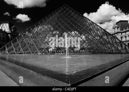 Creative in bianco e nero vista della piramide in vetro e una fontana ingresso al museo del Louvre Parigi Francia Foto Stock