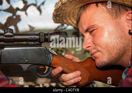 Giovane uomo con arma da fuoco mirando a un bersaglio Foto Stock