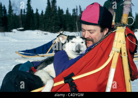 Un affettuoso musher appoggia insieme con il suo husky di piombo in un dogsled dopo la formazione per il sentiero Iditarod Sled Dog Race vicino a Anchorage in Alaska,, Stati Uniti d'America. Foto Stock