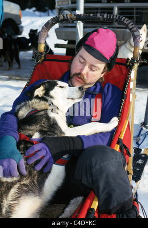 Un affettuoso musher appoggia insieme con il suo husky di piombo in un dogsled dopo la formazione per il sentiero Iditarod Sled Dog Race vicino a Anchorage in Alaska,, Stati Uniti d'America. Foto Stock