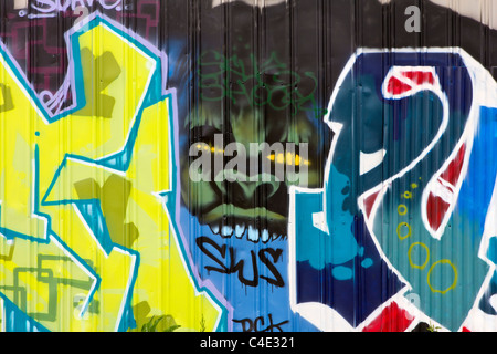 Un mostro verde coetanei attraverso due scribblings graffiti Foto Stock