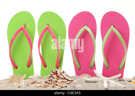 Il flip flop nella sabbia con conchiglie. Estate sul concetto di spiaggia. Foto Stock