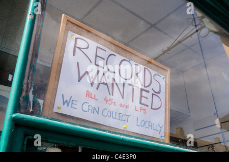 Un segno "Record Wanted' in una carità vetrina Foto Stock