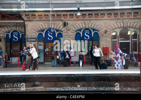 I passeggeri di attendere per un treno alla stazione di Crewe Foto Stock