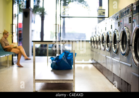 Ragazza in attesa per il lavaggio in lavanderie a gettoni Foto Stock