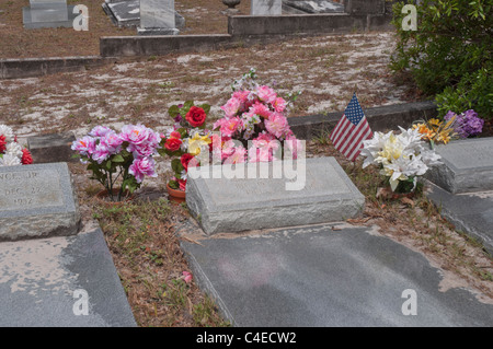 Fiori artificiali e bandiera americana contrassegnare il gravesites nel cimitero di Carrabelle lungo la costa del Golfo della Florida. Foto Stock