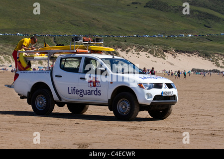 RNLI bagnini; Royal National scialuppa di salvataggio istituzione veicolo e riflessioni sull'estate spiaggia a Woolacombe Bay Beach, Devon, Regno Unito Foto Stock