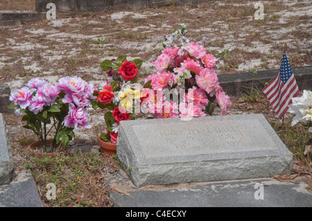 Fiori artificiali e bandiera americana contrassegnare il gravesites nel cimitero di Carrabelle lungo la costa del Golfo della Florida. Foto Stock